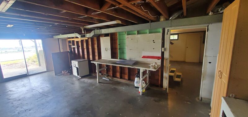 Partially finished basement with workbench and storage